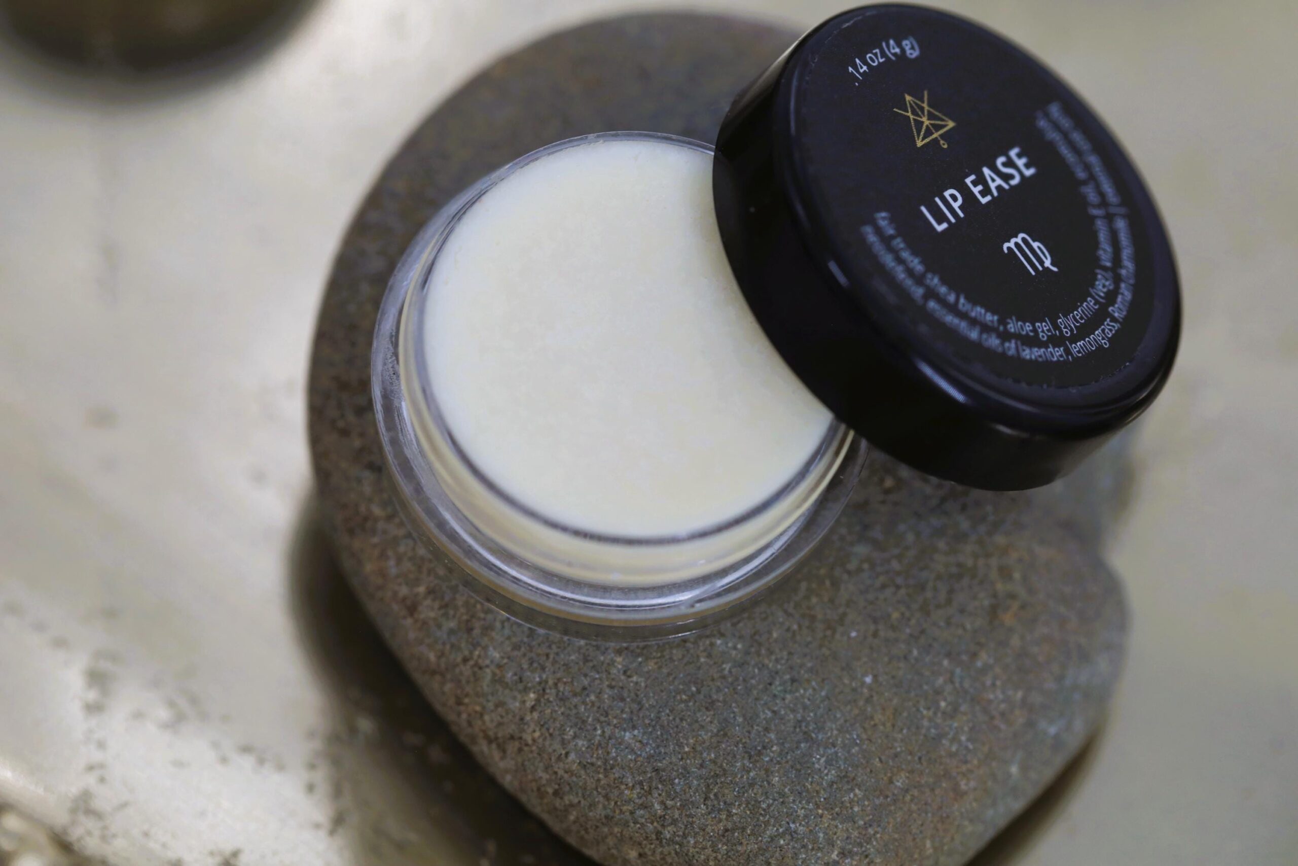 An open jar of Lip Ease sits on a stone.