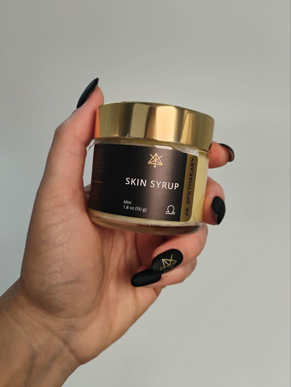 A hand holds a Mini jar of Skin Syrup.