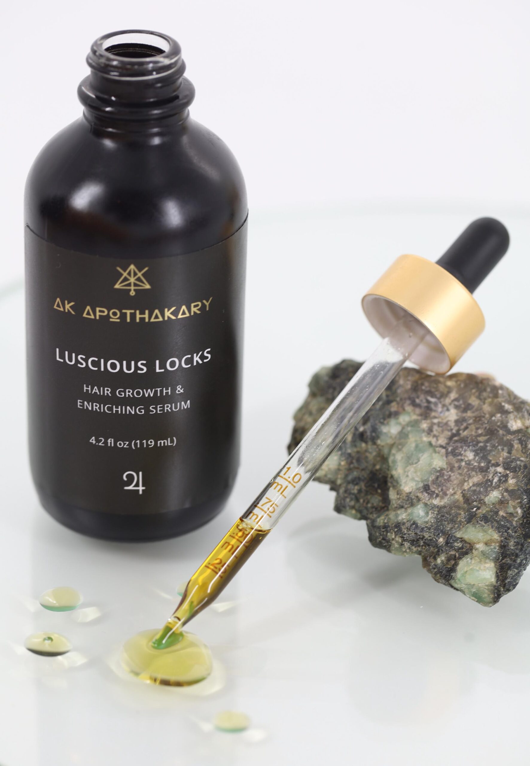 An open eyedropper bottle of Luscious Locks with its dropper resting on a crystal.