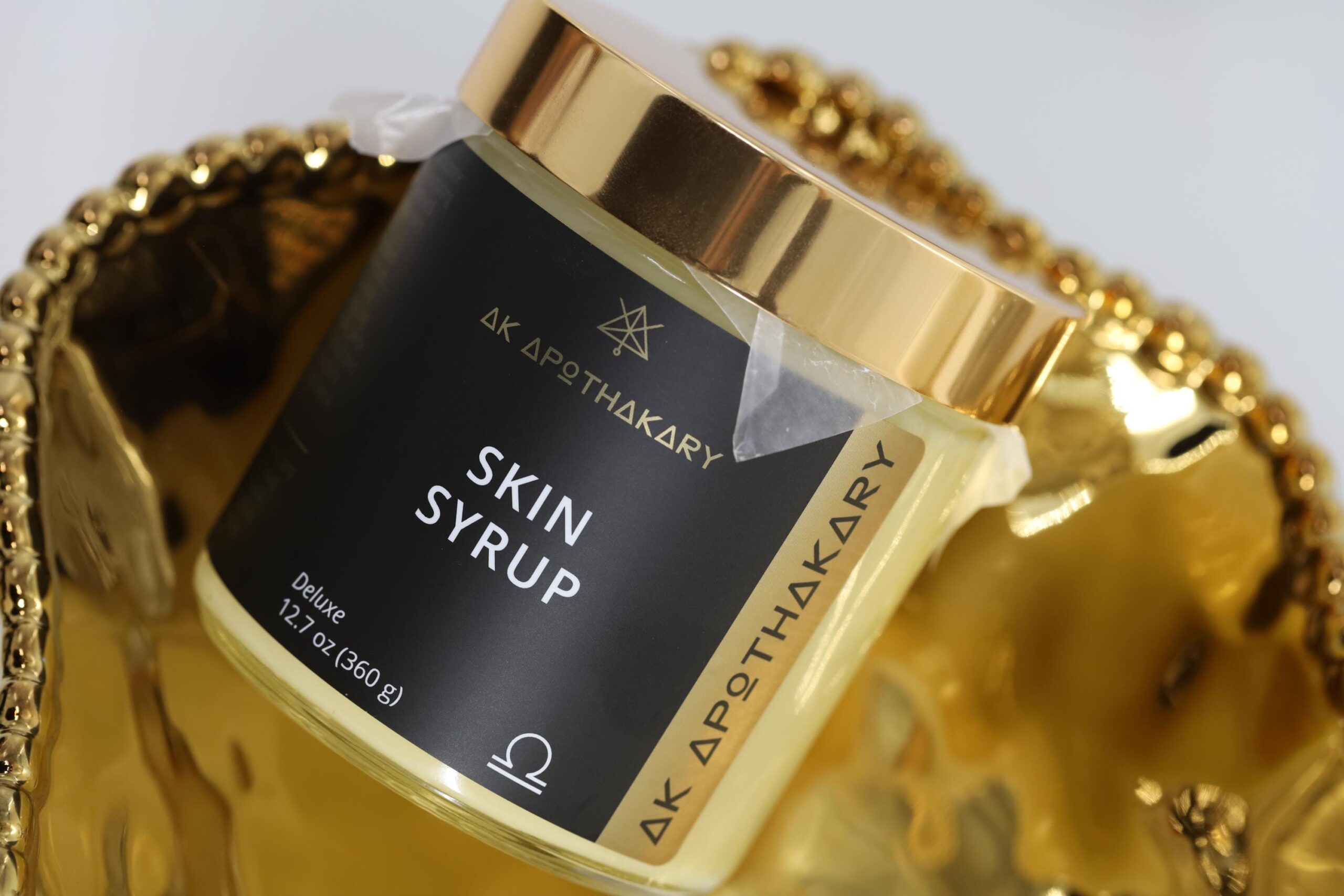 A jar of Skin Syrup sits at an angle on a gold tray.